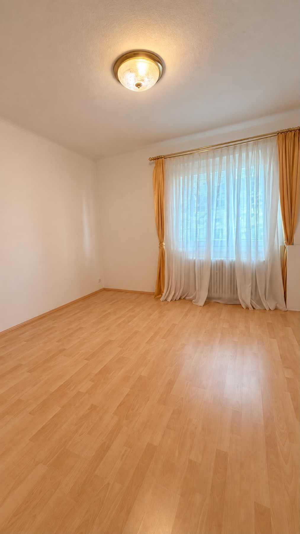 Empty second bedroom with laminate floor and curtained window